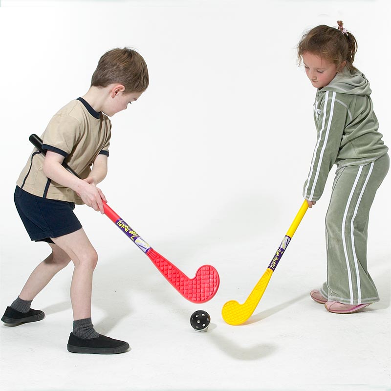 Two young children play with the Eurohoc Floorball Zone Hockey Set, using red and yellow lightweight sticks from Eurohoc, facing off over a black ball on a white background.